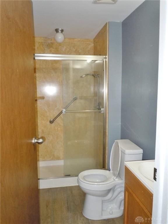 bathroom featuring a shower with door, vanity, and toilet