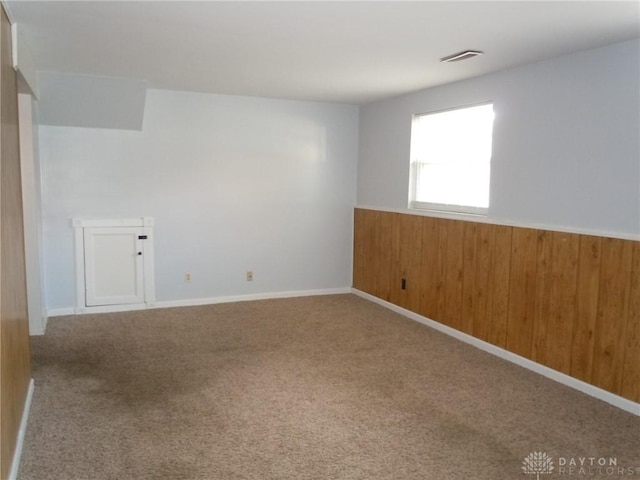 carpeted empty room with wooden walls