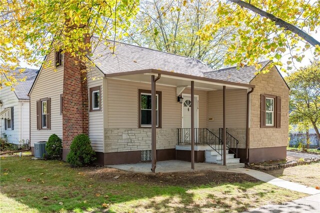 view of front facade with a porch, a front lawn, and central AC unit