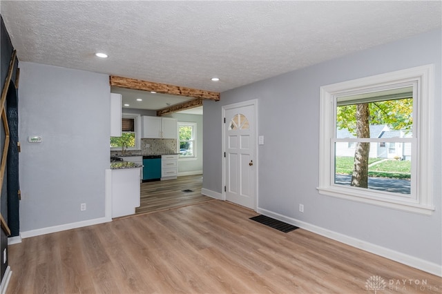 unfurnished living room featuring light hardwood / wood-style flooring and a textured ceiling