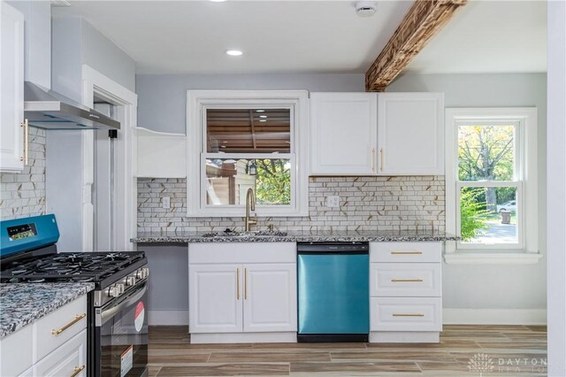 kitchen with sink, stone countertops, wall chimney range hood, and stainless steel appliances