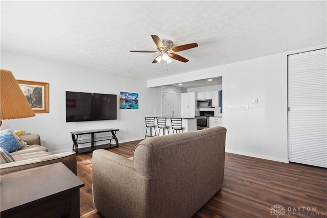 living room with ceiling fan, dark hardwood / wood-style flooring, and a textured ceiling