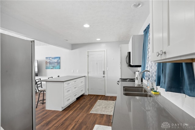 kitchen featuring white cabinets, a kitchen breakfast bar, sink, dark hardwood / wood-style floors, and kitchen peninsula