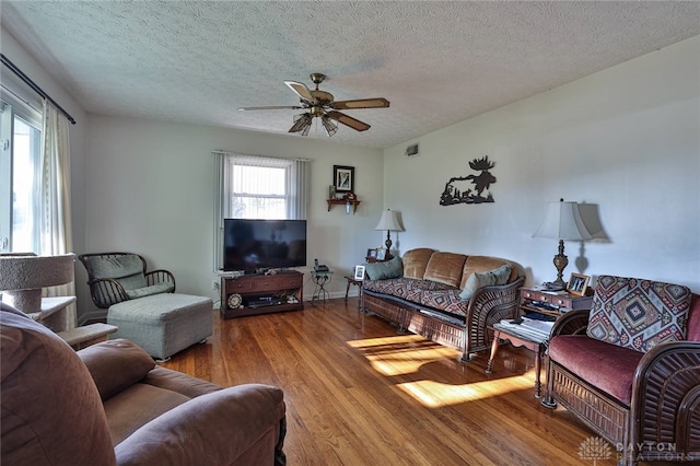 living room featuring a textured ceiling, hardwood / wood-style flooring, and ceiling fan