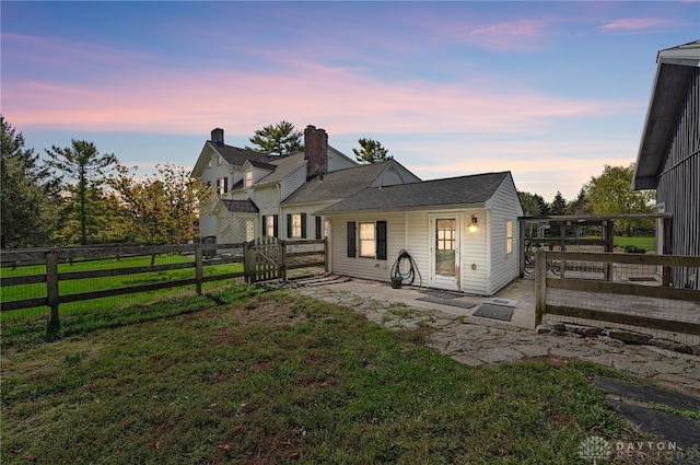 back house at dusk featuring a yard, a deck, and a patio