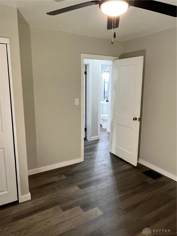 empty room with ceiling fan and dark wood-type flooring