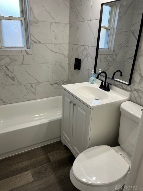 full bathroom with tub / shower combination, hardwood / wood-style floors, toilet, vanity, and tile walls