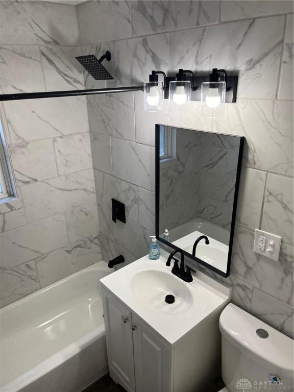 full bathroom with vanity, tiled shower / bath combo, and toilet