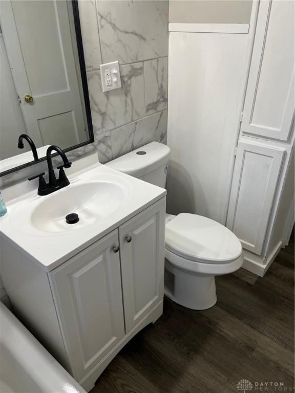 bathroom featuring hardwood / wood-style floors, vanity, tile walls, and toilet