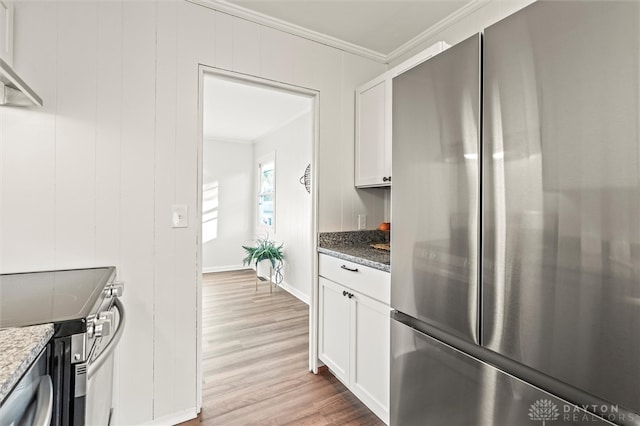 kitchen featuring white cabinets, stainless steel appliances, light wood-type flooring, and dark stone countertops