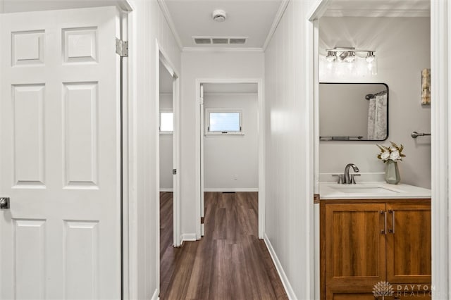 corridor with ornamental molding, sink, and dark wood-type flooring