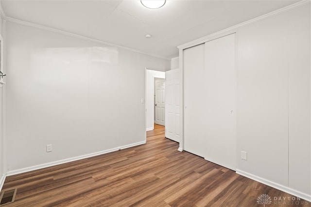 unfurnished bedroom featuring dark wood-type flooring, a closet, and ornamental molding