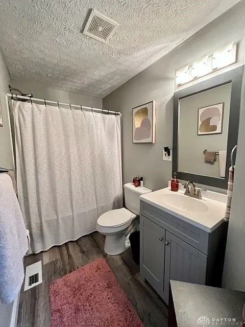 bathroom with vanity, a textured ceiling, hardwood / wood-style flooring, and toilet