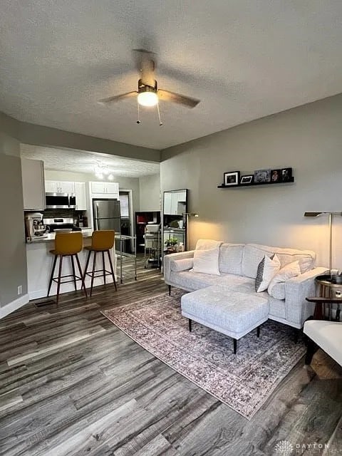 living room featuring a textured ceiling, wood-type flooring, and ceiling fan