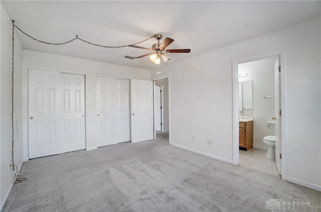 unfurnished bedroom with ensuite bath, light carpet, multiple closets, and ceiling fan