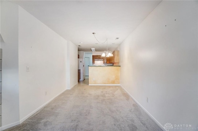 unfurnished living room with a chandelier and light colored carpet