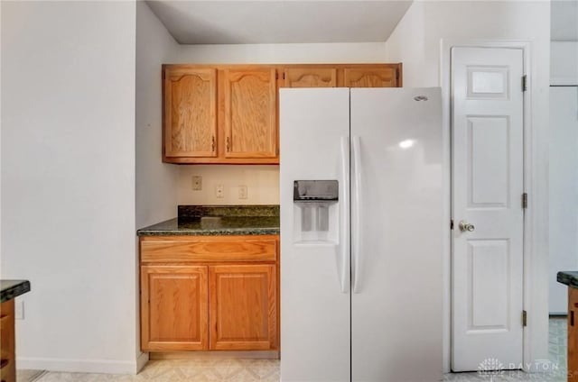 kitchen with dark stone countertops and white fridge with ice dispenser