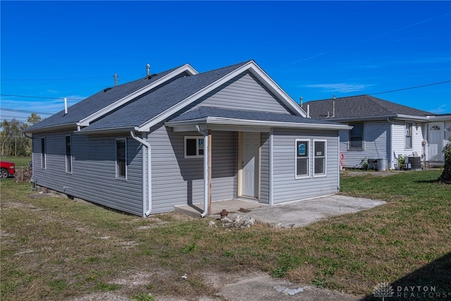 back of property featuring central AC unit, a patio area, and a lawn