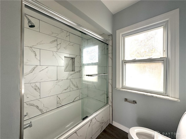 bathroom featuring toilet, wood-type flooring, and enclosed tub / shower combo