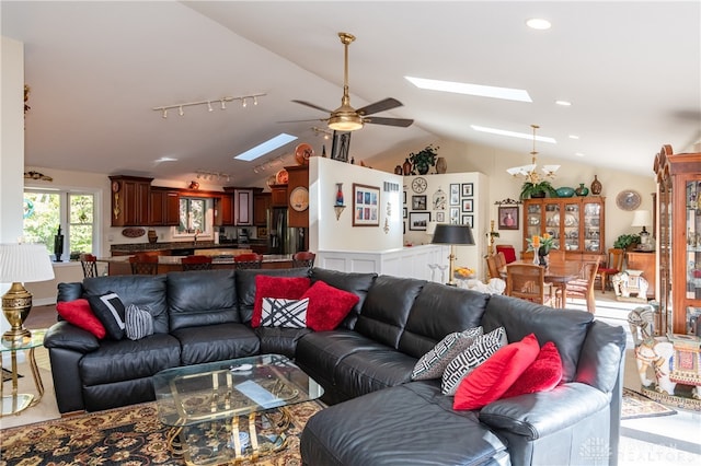 living room featuring vaulted ceiling with skylight, sink, and ceiling fan