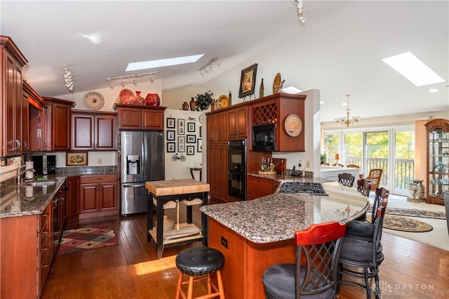 kitchen with lofted ceiling with skylight, black appliances, a center island, and dark hardwood / wood-style floors