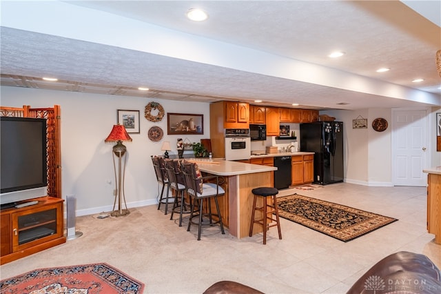 kitchen with kitchen peninsula, black appliances, a kitchen bar, light colored carpet, and a textured ceiling