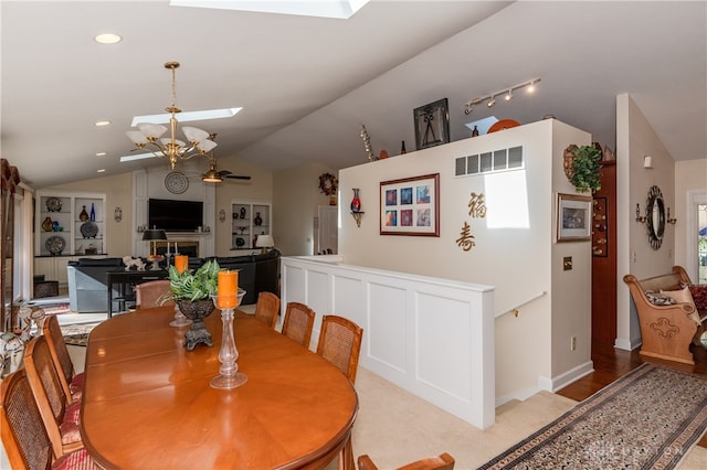 dining area with lofted ceiling with skylight and ceiling fan with notable chandelier