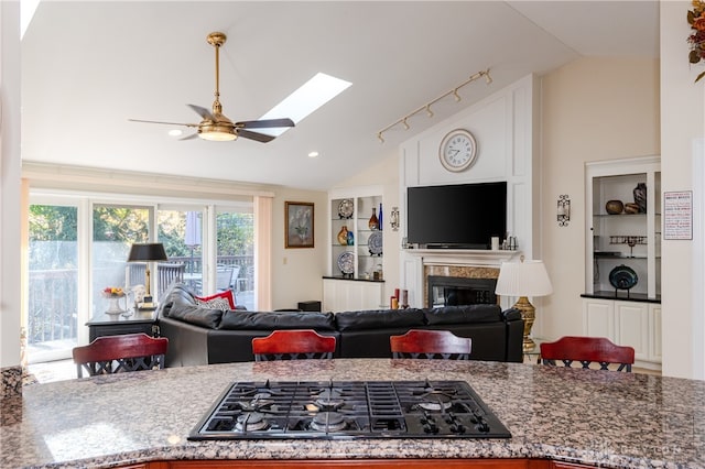 kitchen with black gas stovetop, lofted ceiling with skylight, white cabinets, and ceiling fan