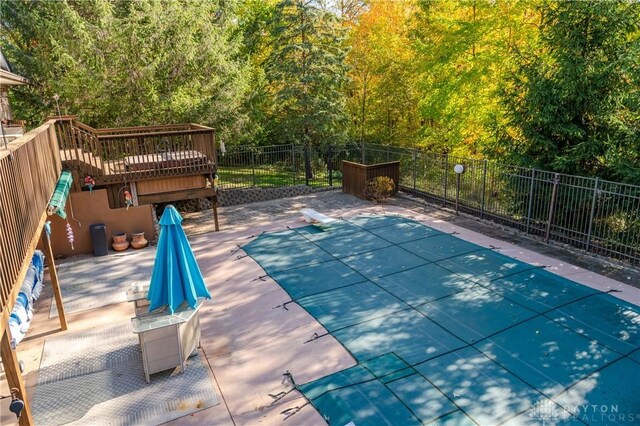 view of swimming pool with a diving board and a patio area