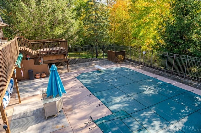 view of swimming pool with fence, a diving board, and a wooden deck