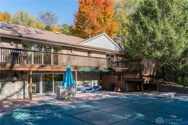 back of house with a patio area, a wooden deck, and a covered pool