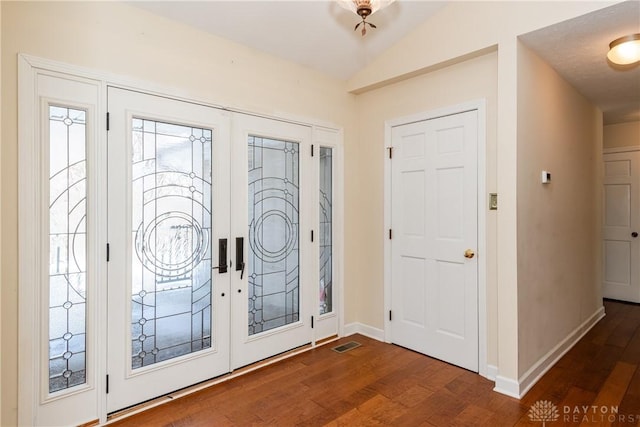 foyer with french doors, lofted ceiling, visible vents, dark wood-type flooring, and baseboards