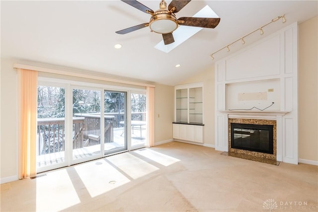 unfurnished living room with light carpet, a premium fireplace, baseboards, vaulted ceiling, and track lighting