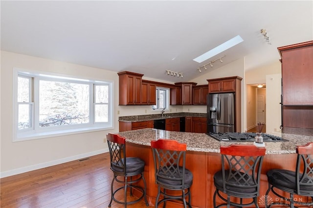 kitchen featuring stainless steel appliances, lofted ceiling with skylight, a peninsula, and a breakfast bar area