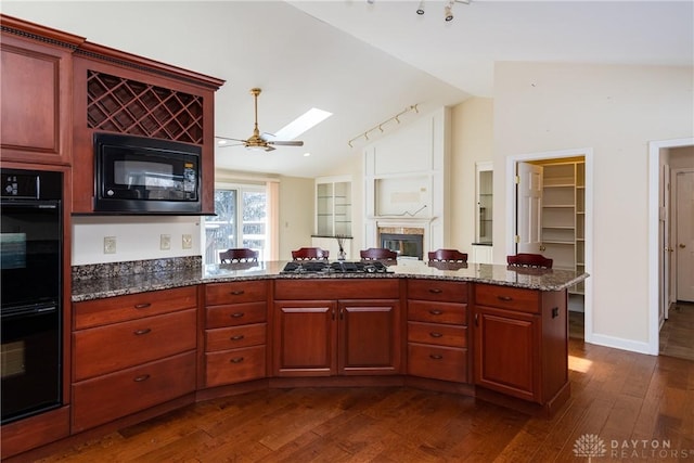 kitchen featuring dark wood-style flooring, lofted ceiling, a ceiling fan, dark stone counters, and black appliances