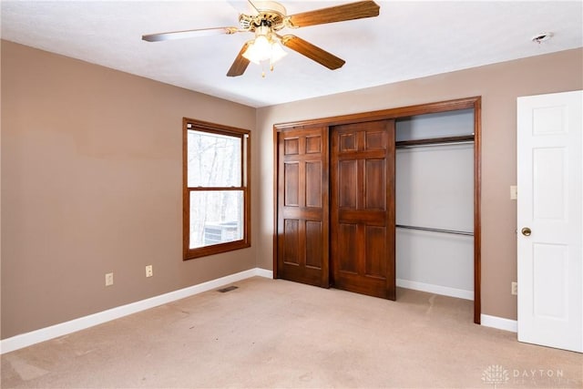 unfurnished bedroom with a closet, light carpet, ceiling fan, and baseboards