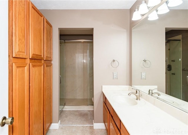 bathroom with an inviting chandelier, a shower stall, baseboards, and vanity