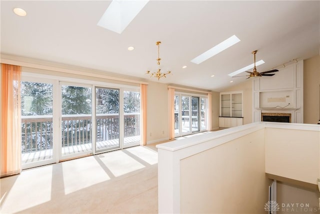 interior space featuring vaulted ceiling with skylight, built in features, open floor plan, hanging light fixtures, and recessed lighting