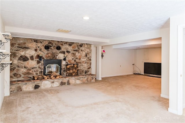 unfurnished living room featuring a textured ceiling, light colored carpet, a fireplace, visible vents, and baseboards