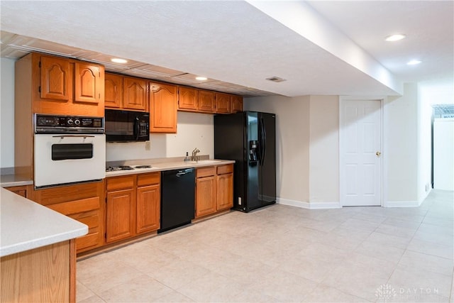 kitchen featuring black appliances, recessed lighting, light countertops, and brown cabinetry