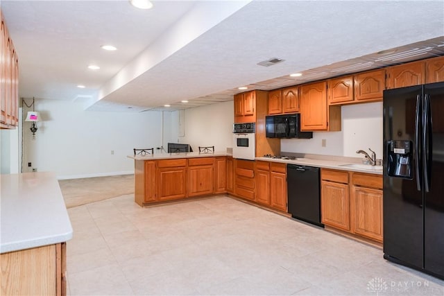 kitchen with brown cabinetry, light countertops, a sink, and black appliances