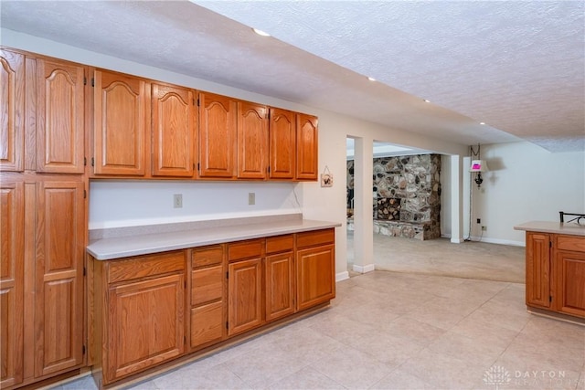 kitchen with brown cabinets, light countertops, and a textured ceiling