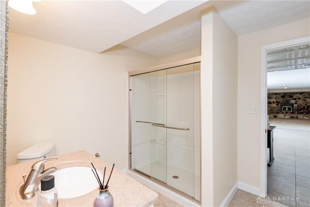 bathroom featuring a sink, a shower stall, toilet, and baseboards