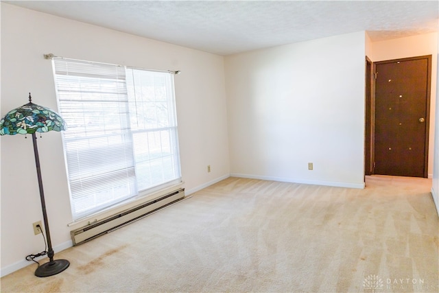 spare room with light carpet, a textured ceiling, and a baseboard radiator