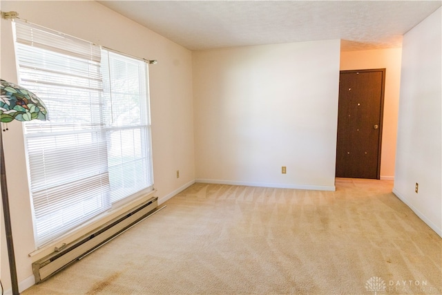 spare room featuring light colored carpet, a baseboard radiator, and a wealth of natural light