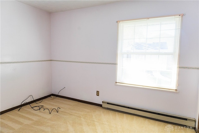 unfurnished room featuring a healthy amount of sunlight, a baseboard heating unit, and light colored carpet