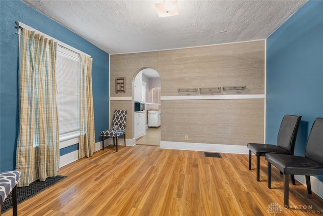 living area with light hardwood / wood-style floors, wood walls, and a textured ceiling