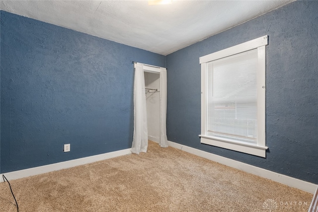 unfurnished bedroom featuring a closet, carpet, and a spacious closet