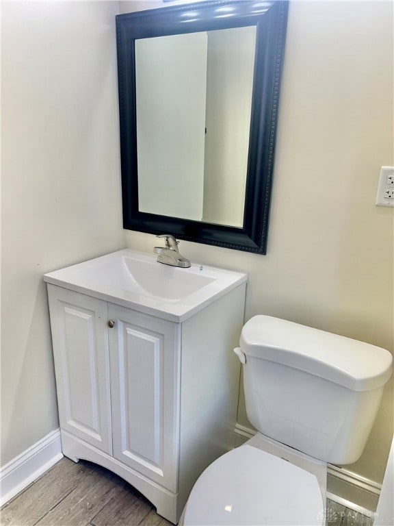 bathroom with vanity, toilet, and hardwood / wood-style flooring