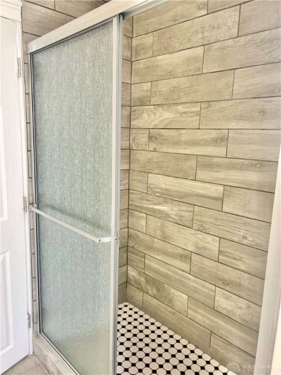 bathroom featuring wooden walls and an enclosed shower